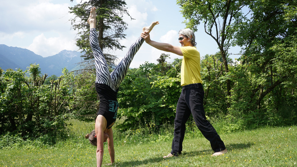 Nun schiebt der Handstandübende in das gehaltene Bein und hebt das andere Bein hoch zur Decke.